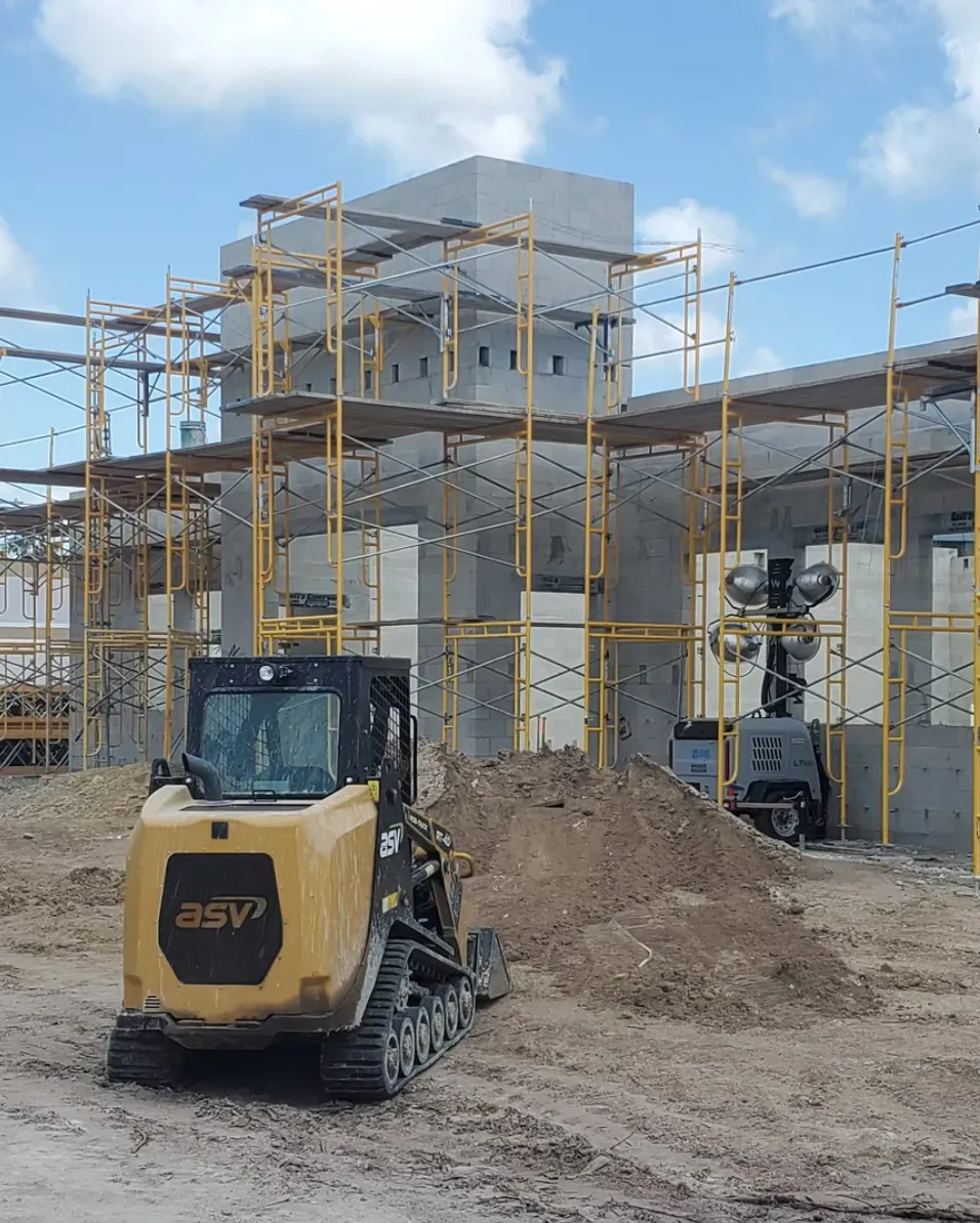 Bobcat in front of large block construction project